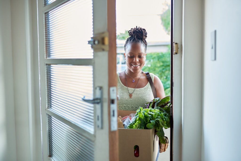 A young carer arrives with a box of groceries