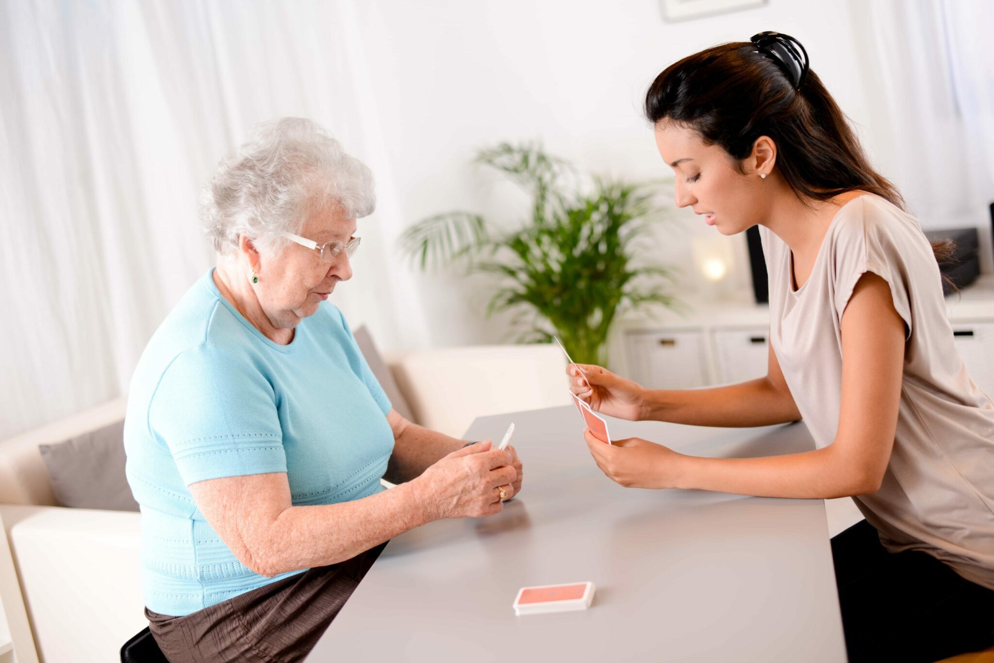 Elderly woman playing cards with her carer