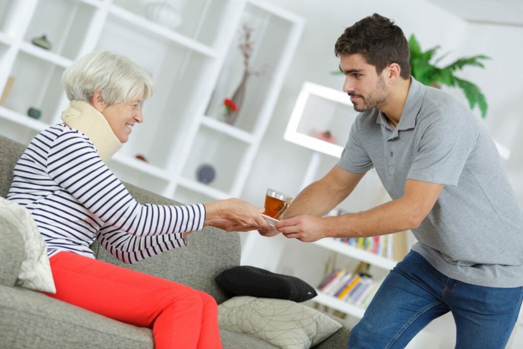 Carer helping elderly woman post-operation