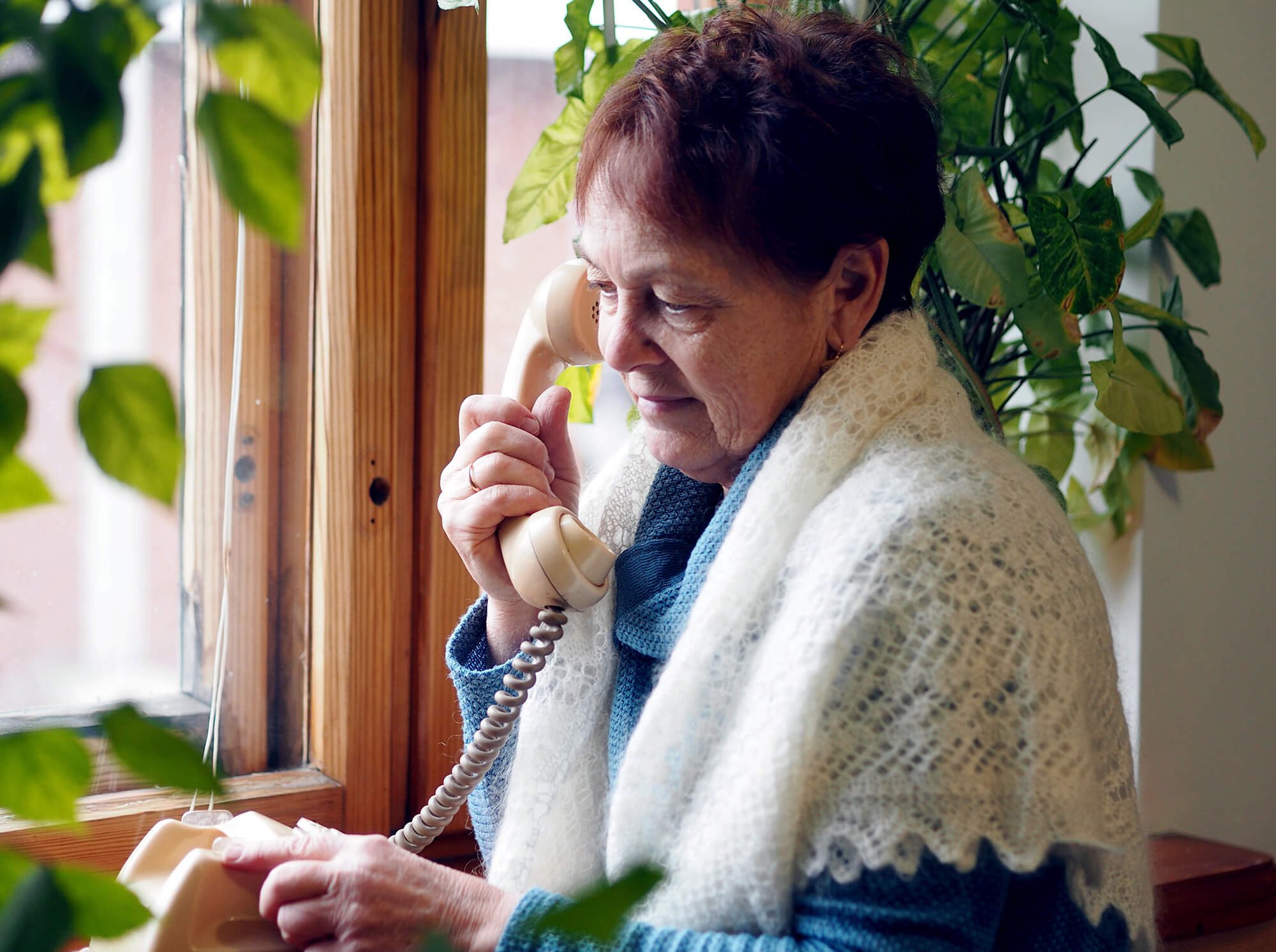 Elderly woman waits on phone for her call to be answered