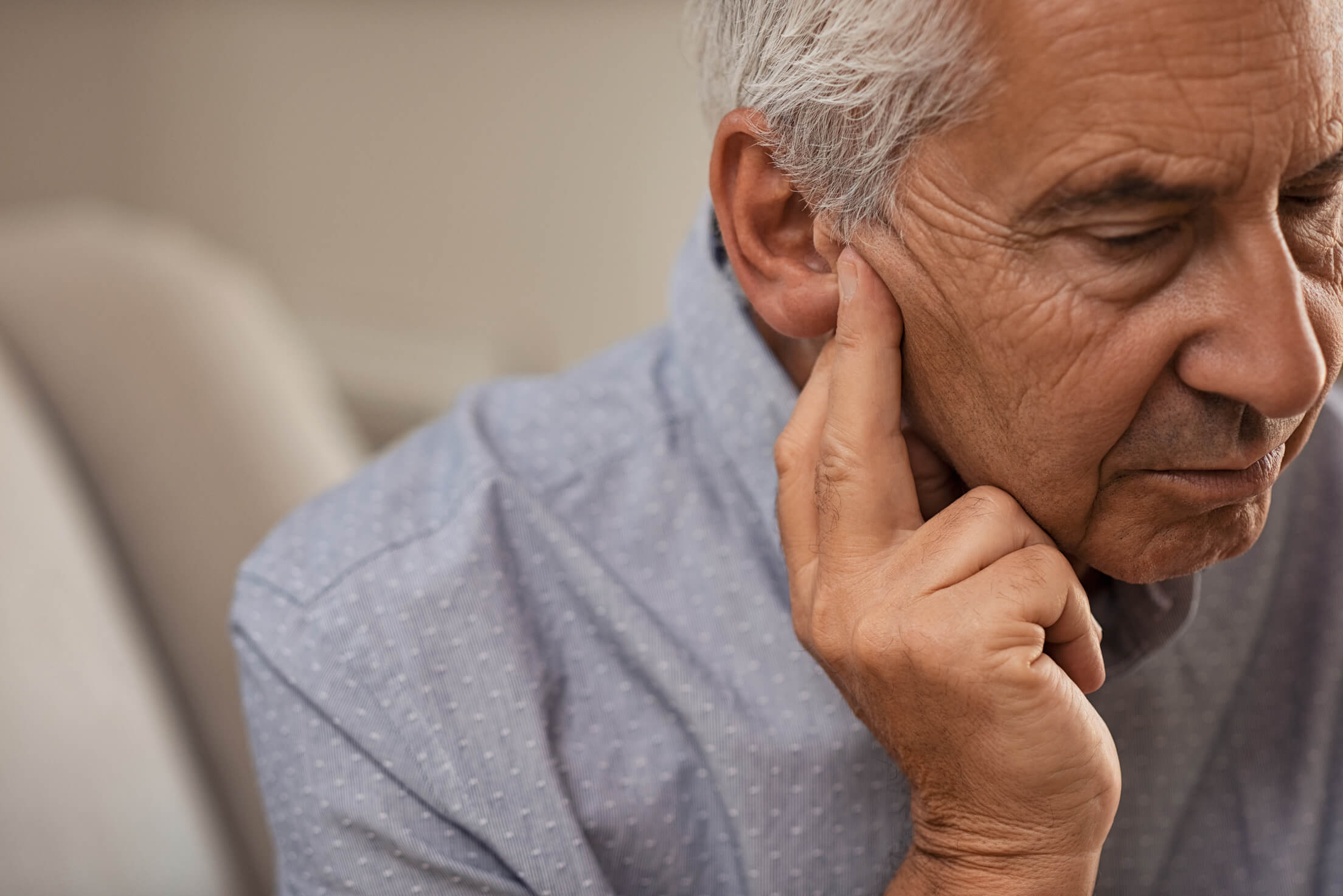 Old man holding his ear in discomfort.