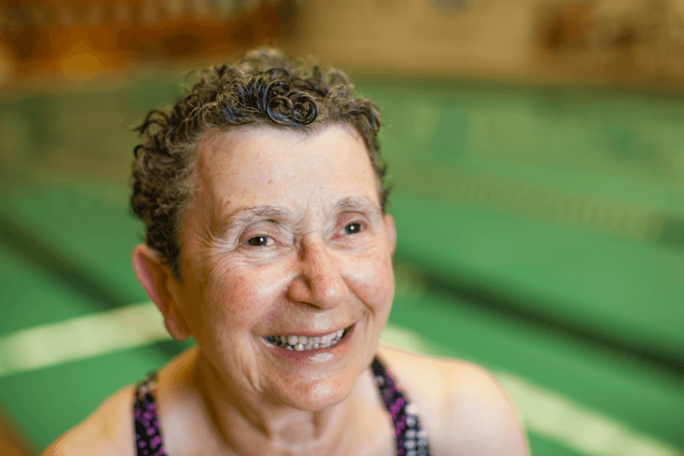 An elderly woman smiling in a public swimming pool
