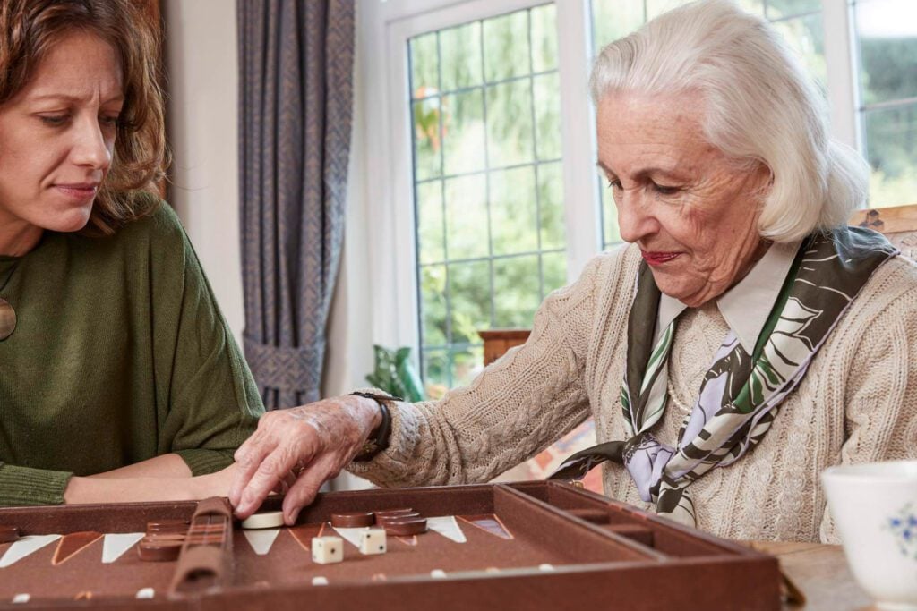 An elderly woman playing board games with her carer