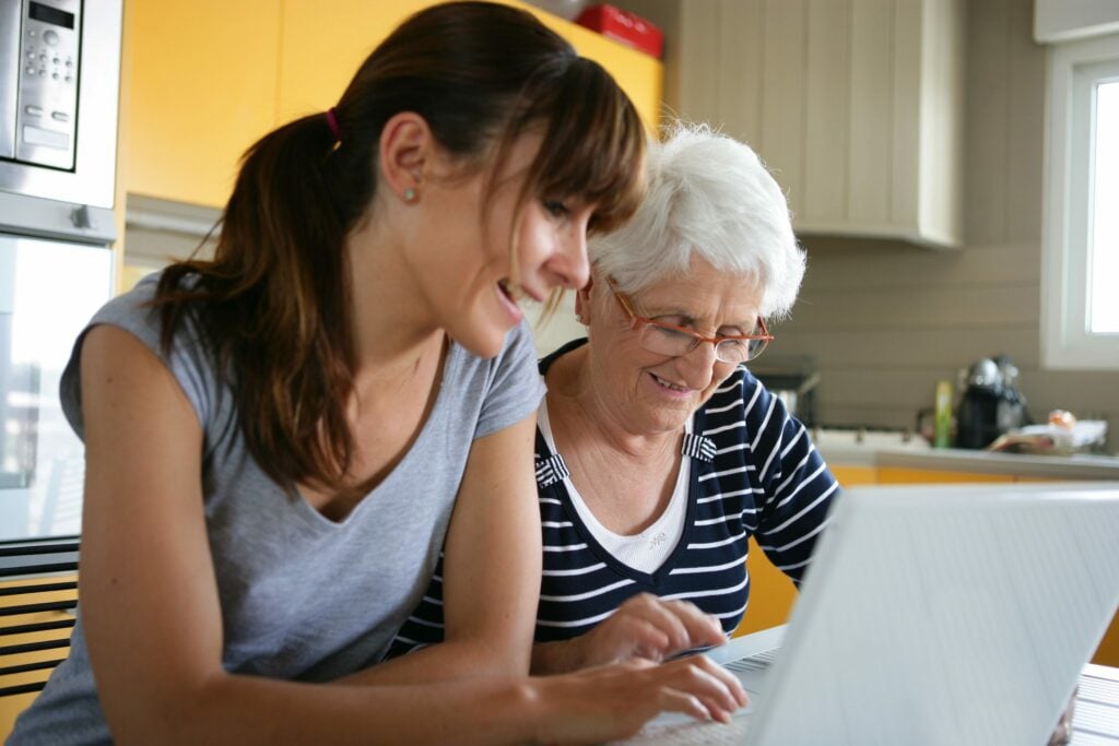 Woman with elderly relative looking at care options available online