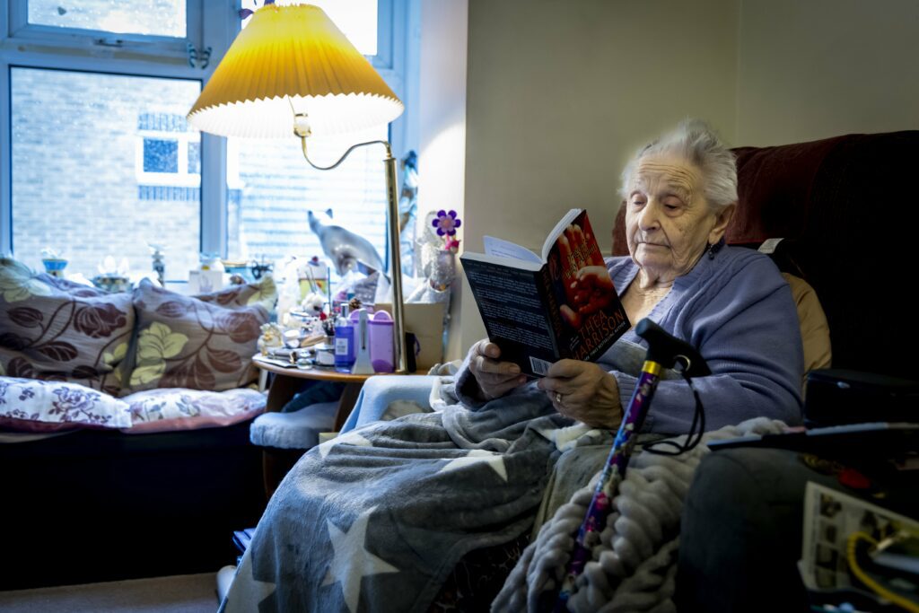 An Older Woman Reading at Home Under a Blanket, Recently discharged from Hospital