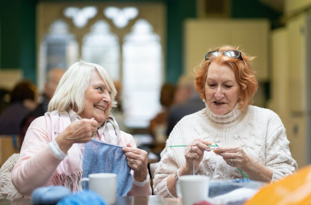 Two Older Woman Knitting together at a social club