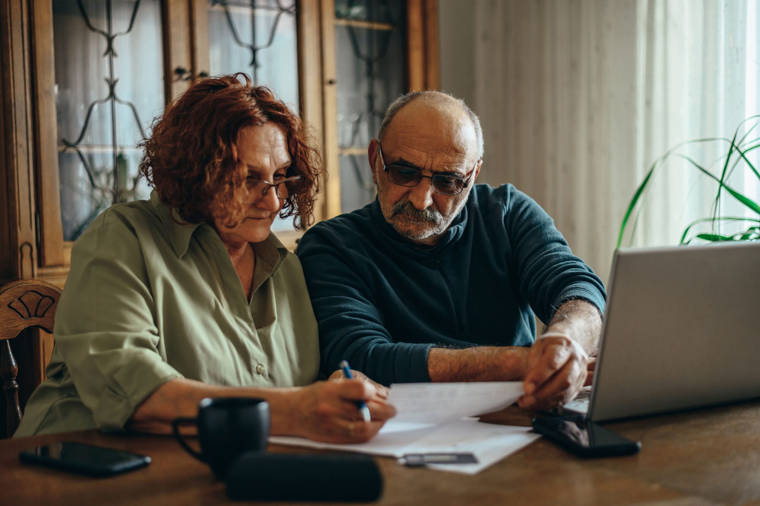 An Elderly couple doing some paperwork together at home.