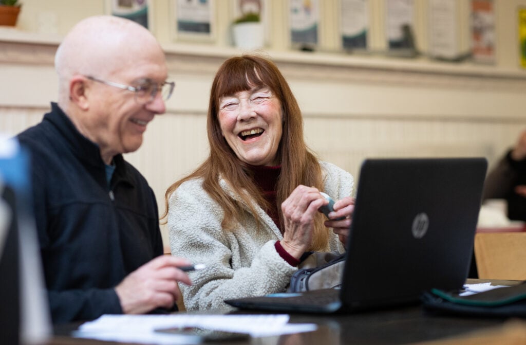 A Man and Woman in a Local Library Using a Computer and Laughing