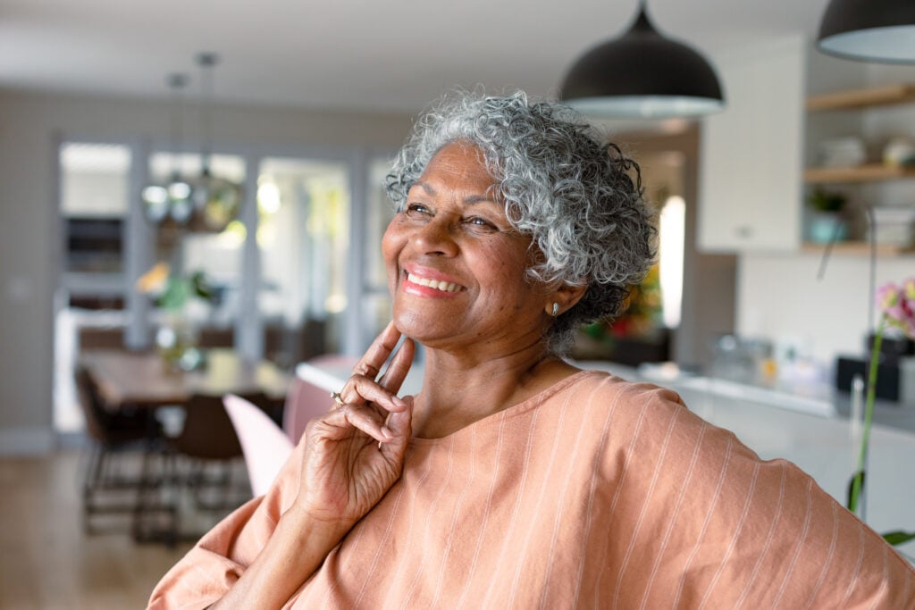 Happy senior woman standing and touching her face