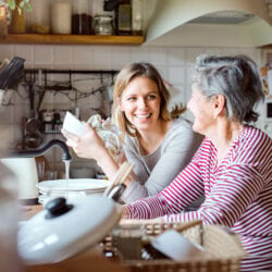 A young woman and her grandmother washing and drying dishes together at the kitchen sink