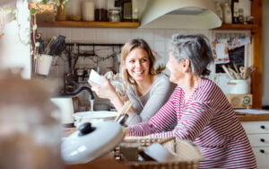 A young woman and her grandmother washing and drying dishes together at the kitchen sink