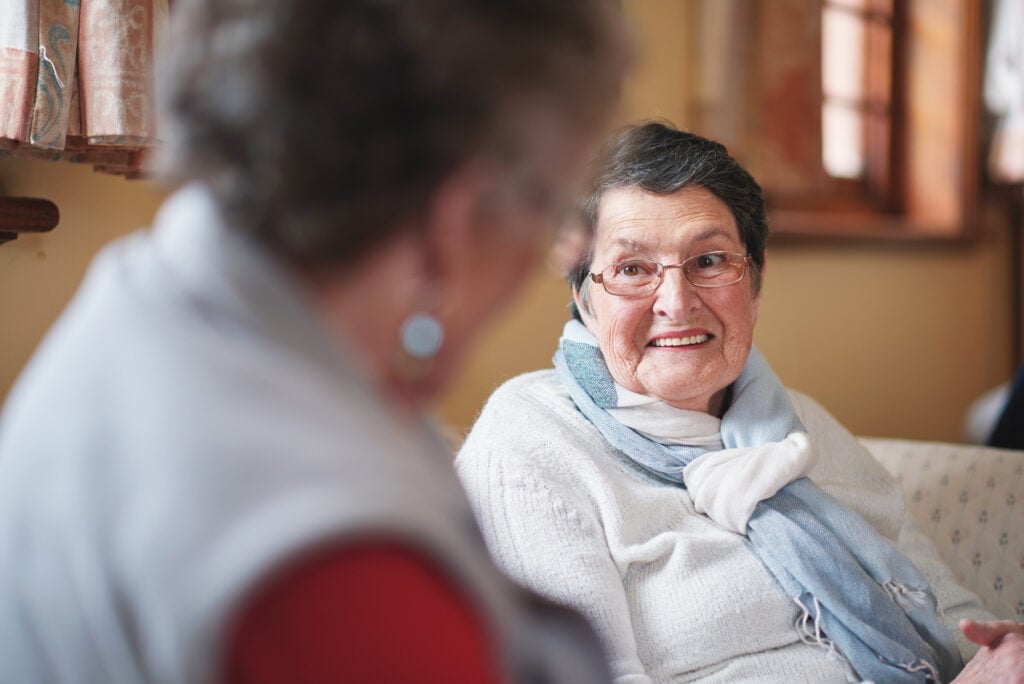 Older woman smiling at friend in conversation in a local church hall