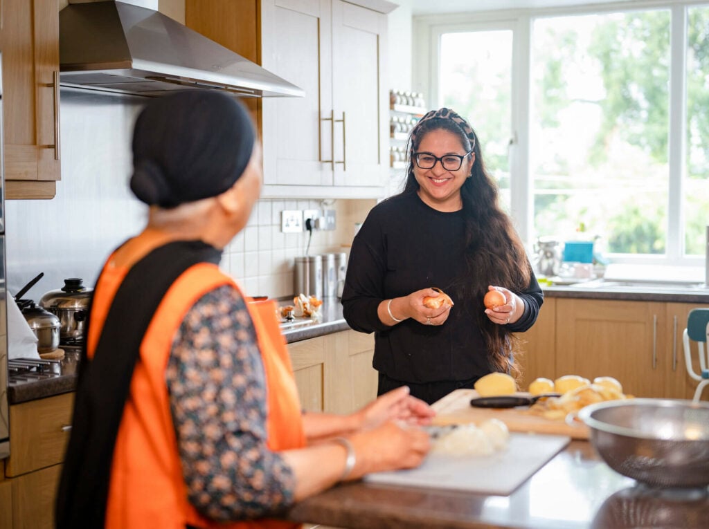 An asian woman helping an older lady to prepare a meal in the kitchen