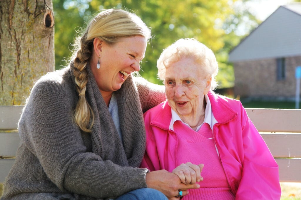 Elderly woman laughing with her carer