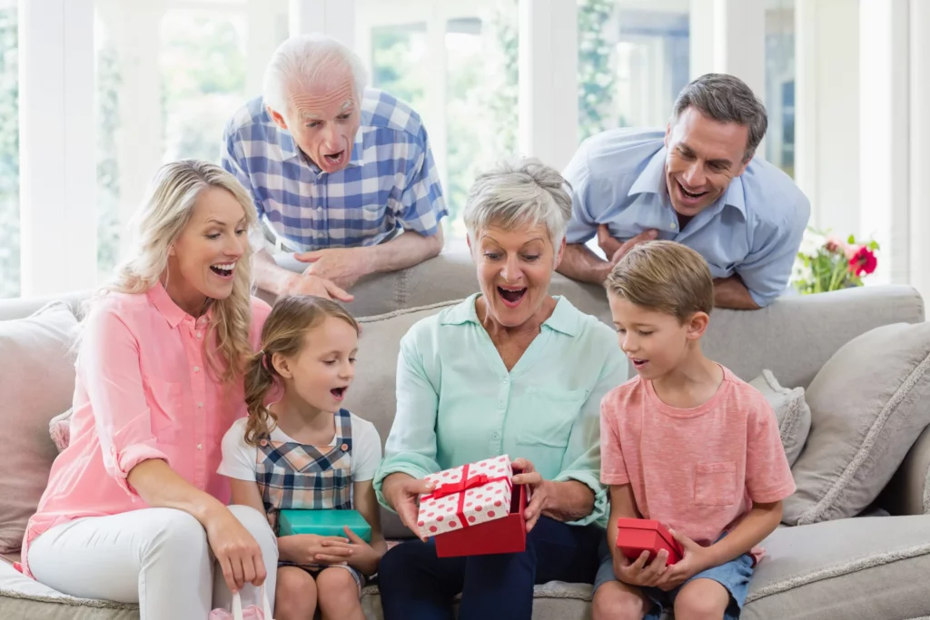 Elderly woman opening a gift with her family